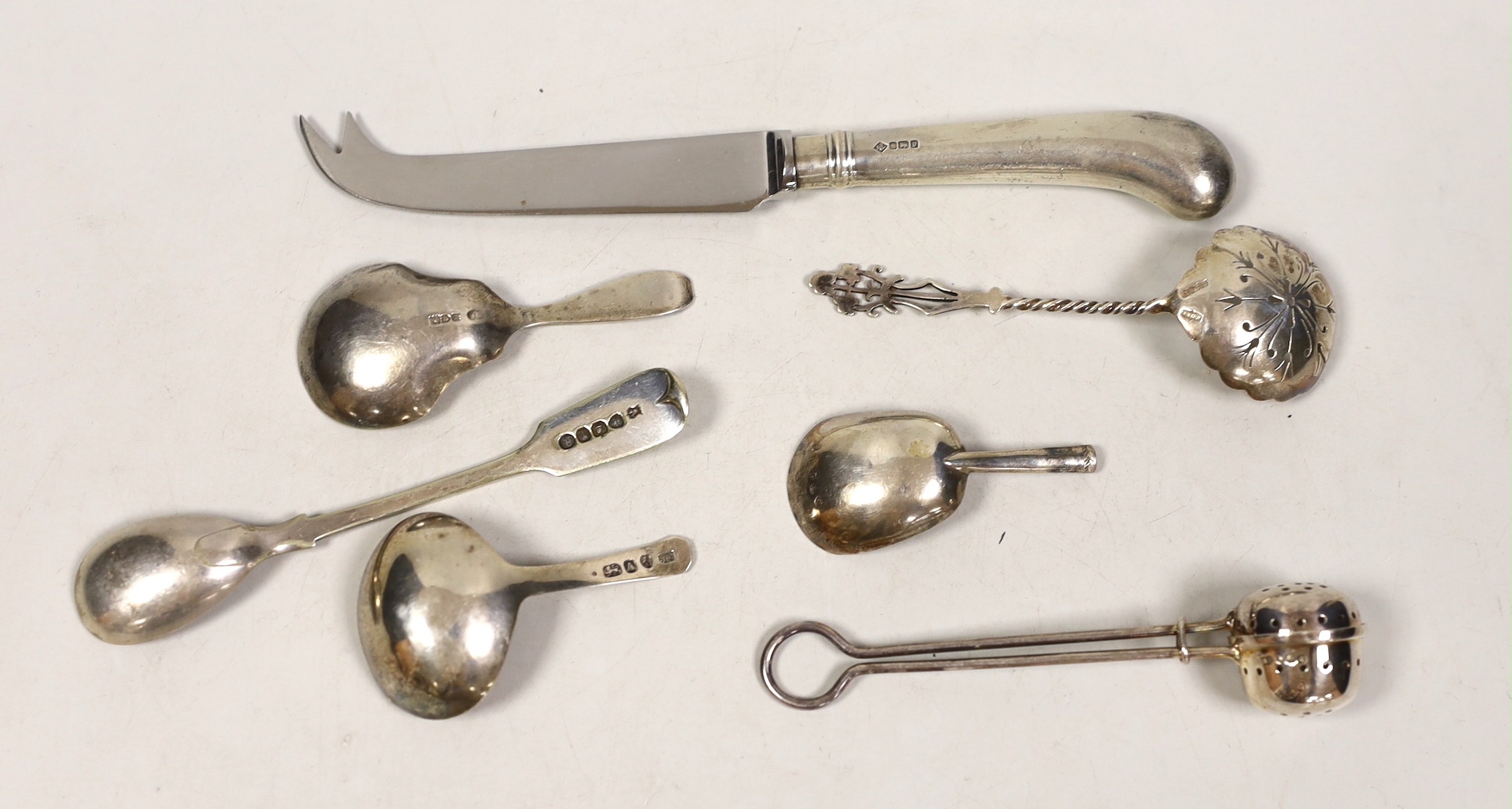 Three silver caddy spoons, including two 19th century, a silver infuser, a sifter spoon, a cheese knife and a plated condiment spoon.
